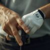 日本人男性ゴルファーがゴルフグローブを装着してクラブを握ろうとしている様子