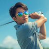 日本人男性ゴルファーが晴天のコースでゴルフ用サングラスをかけてティーショットの構えをしている様子