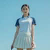 日本人女性ゴルファーがネイビーとホワイトのポロシャツとスコートでゴルフコースに立っている様子